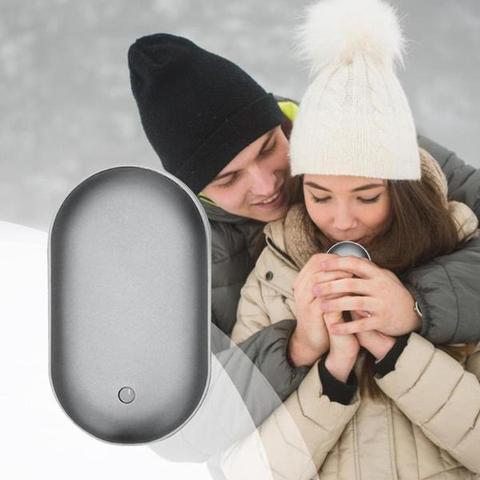 Person holding a small gray device with a couple embracing in the background