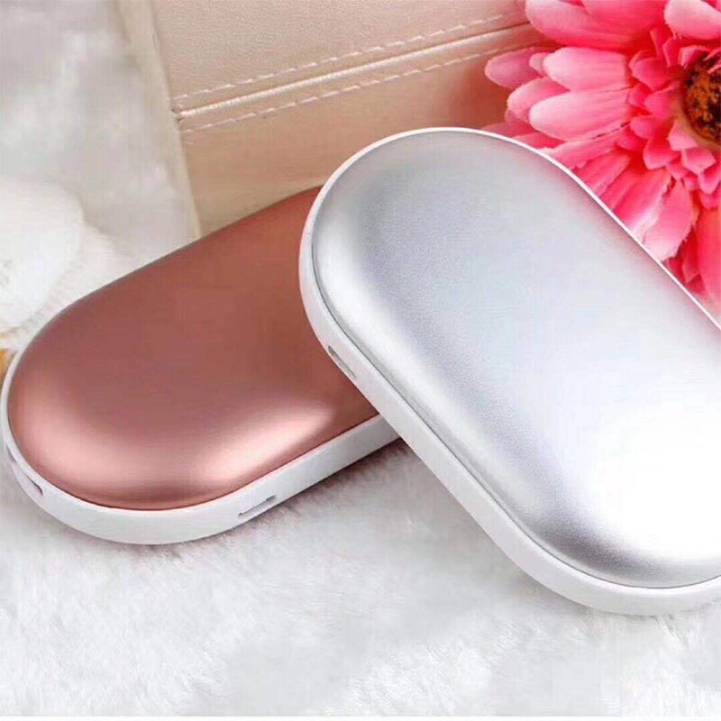 Two handheld warmers, one rose gold and one silver, on a white surface with a pink flower in the background.