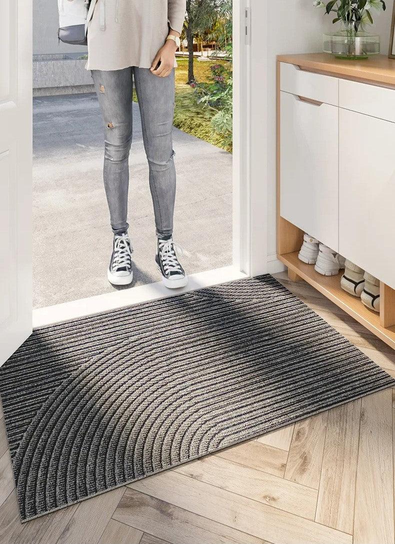 Person stepping onto a textured doormat at the entrance of a home.