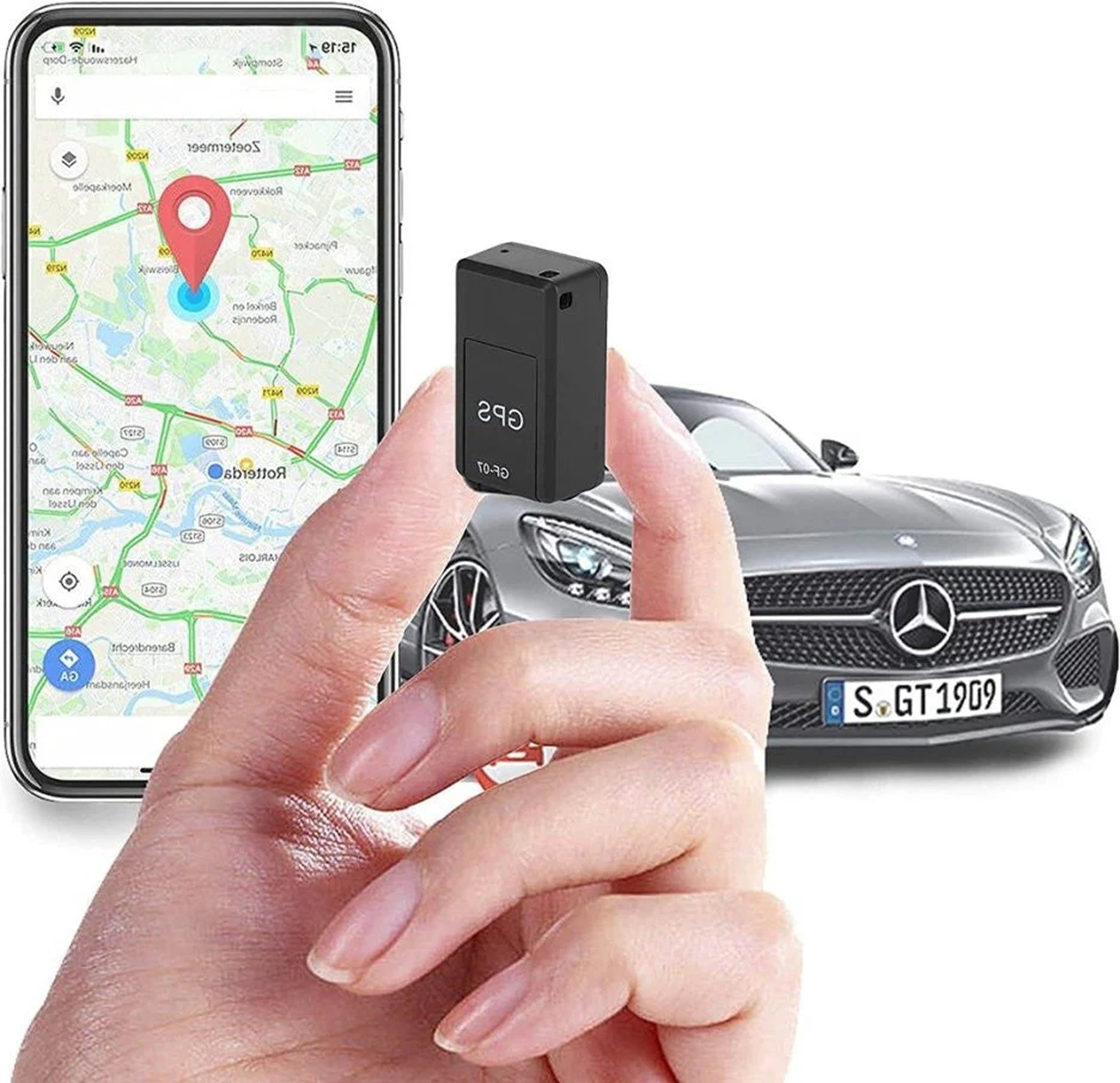Hand holding a small black device with a smartphone displaying a map and a car in the background.