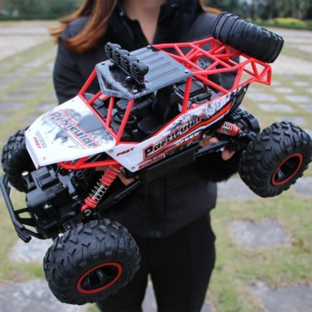 Person holding a remote control monster truck outdoors