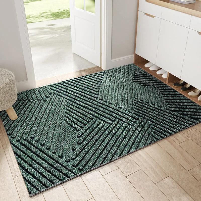 Green doormat with geometric pattern on a wooden floor in a home setting.